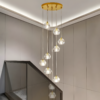 4 Elegant modern chandelier with multiple hanging crystal pendant lights, illuminating a contemporary stairway with glass railing.